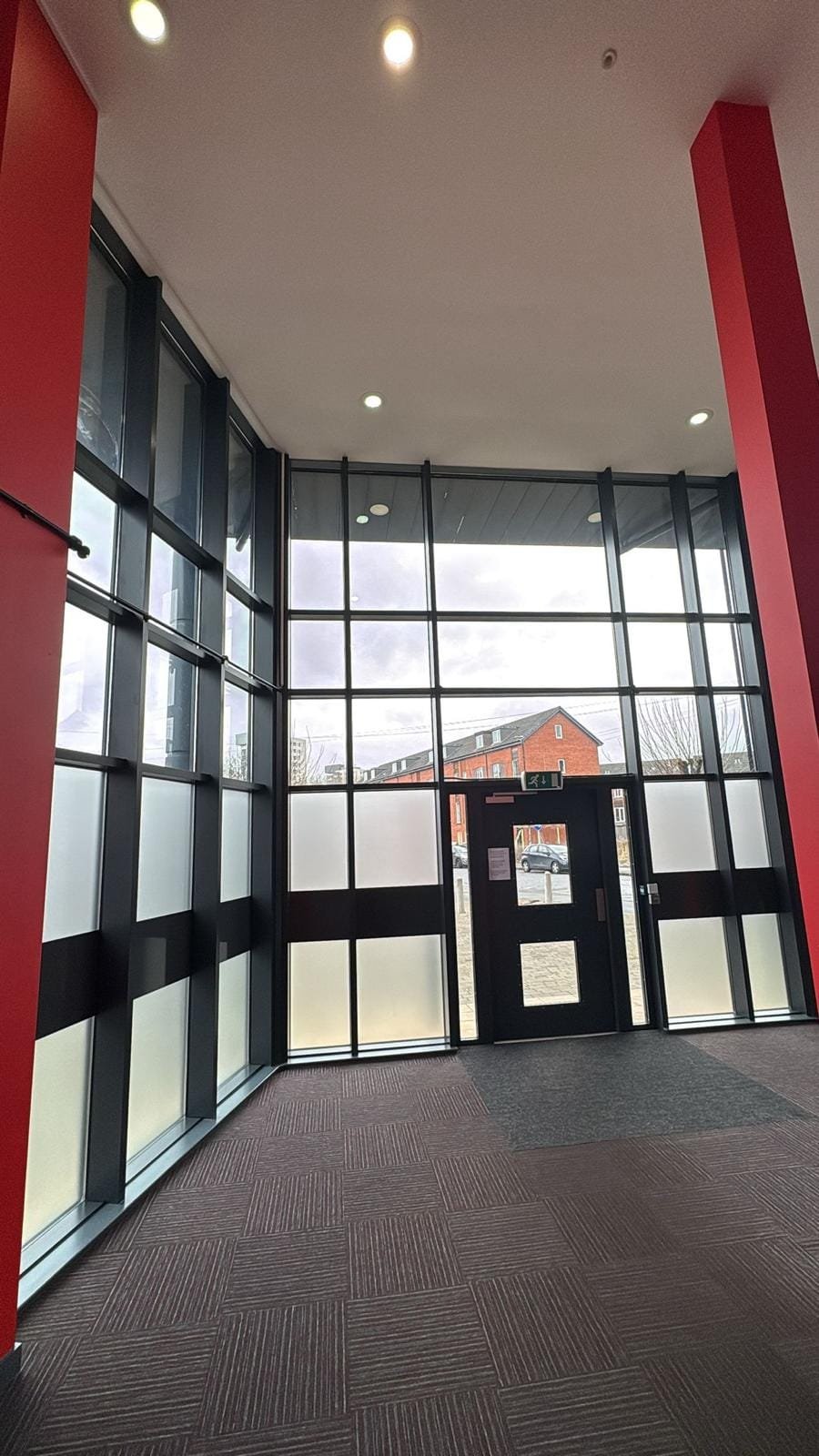 Communal entrance lobby with full-height glazing and a secure door entry point to a residential block