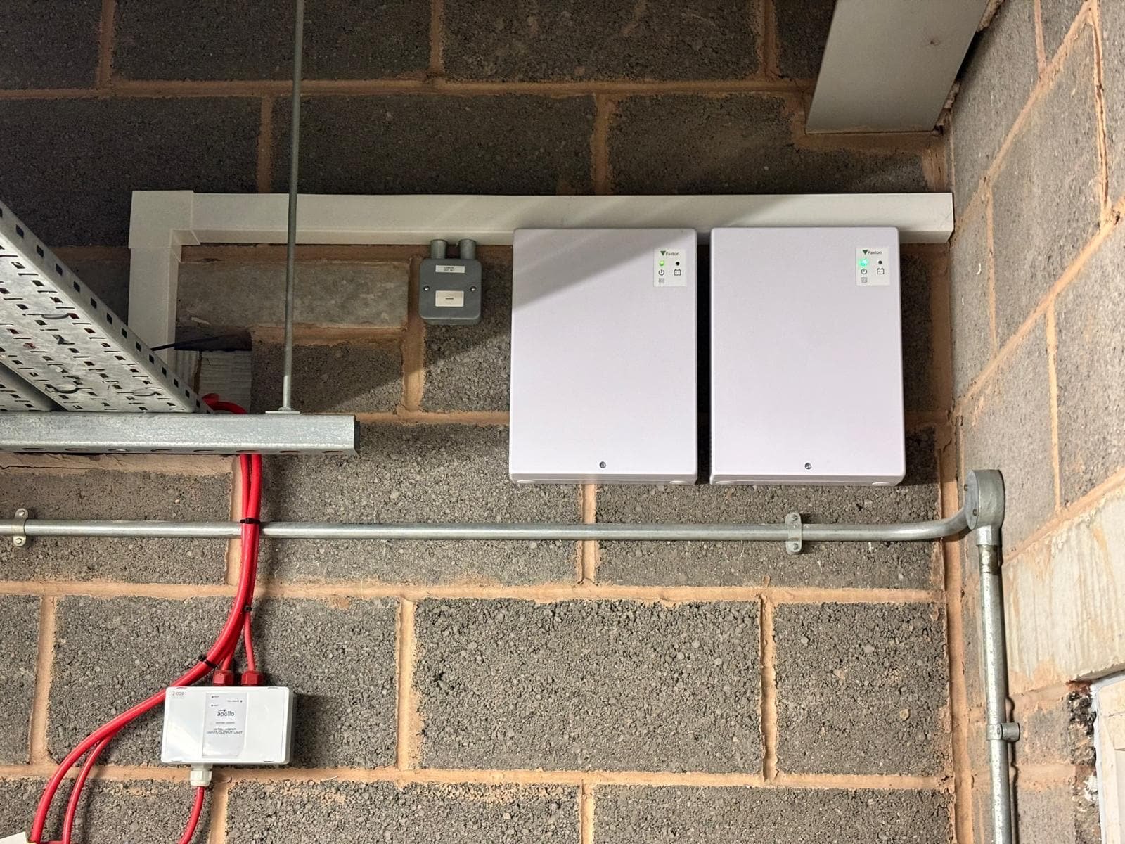 Two wall-mounted Paxton Net2 access control enclosures fed by galvanised conduit and cable tray in a plant room