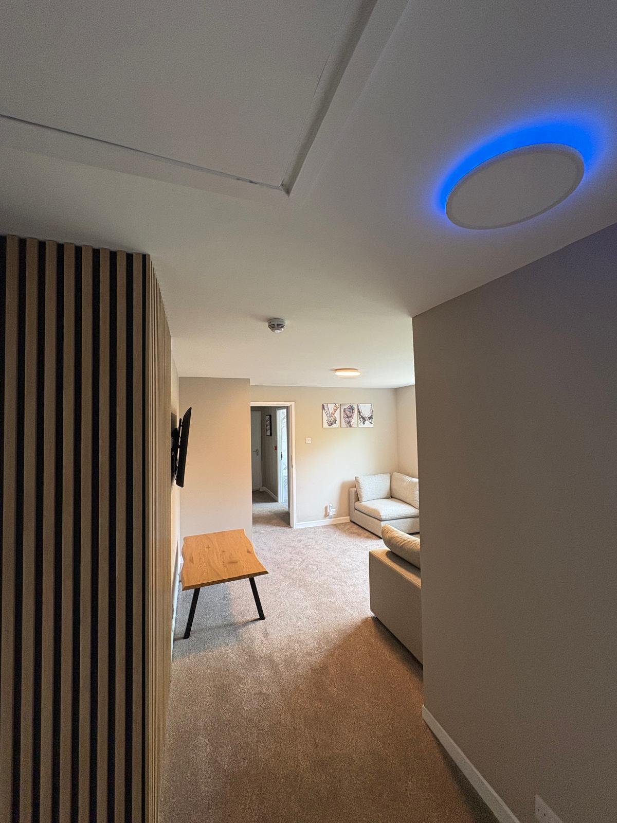 Lounge with colour-change LED ceiling panel showing blue backlight and slatted feature wall