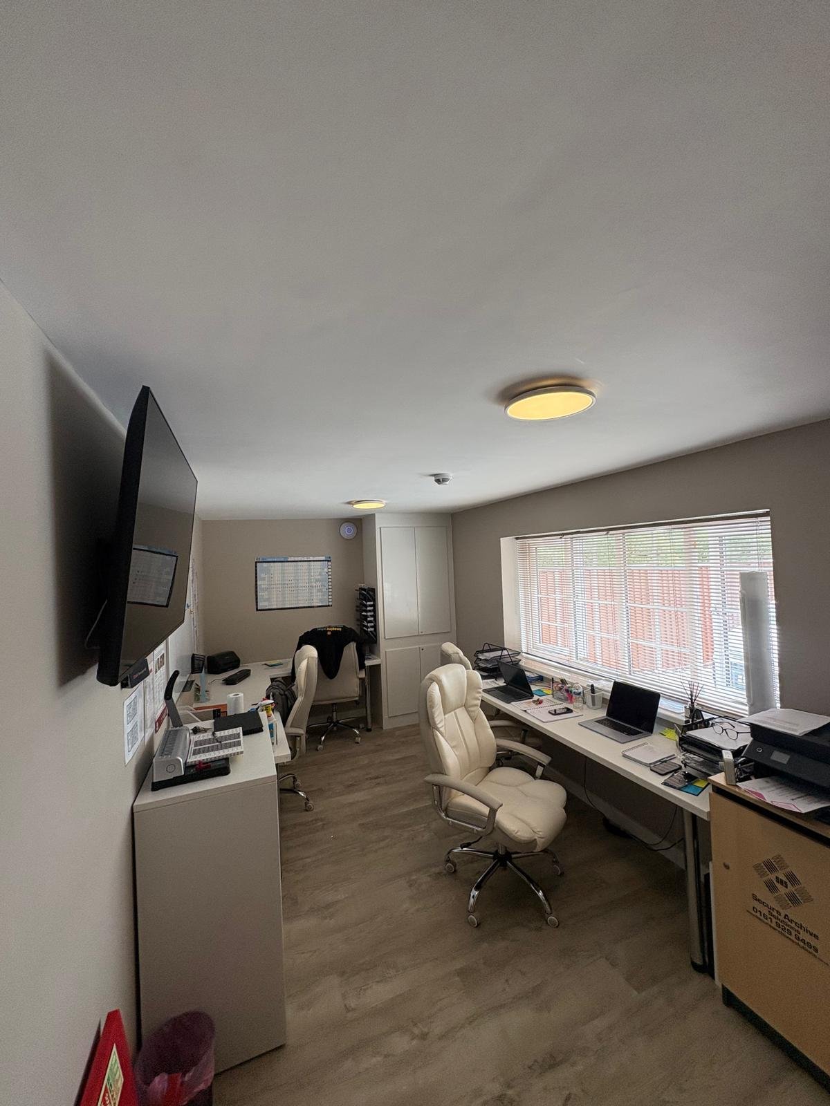 Office fit-out with flush LED ceiling lights, wall-mounted display and desk power outlets